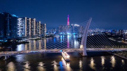 Obraz premium Aerial night, Mekong river delta view of a bridge, illuminated Saigon city skyline skyscrapers view and busy traffic on the main road of Ho Chi Minh
