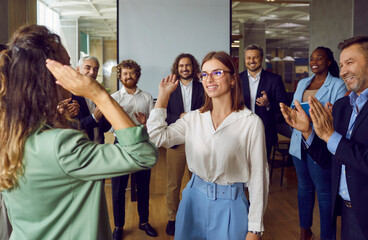 Happy female colleagues giving high five at meeting at the office, celebrating success, making a...
