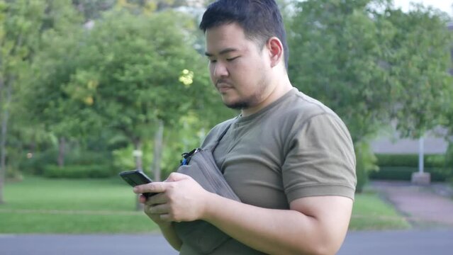 asian man using mobile phone while relaxing in the park.