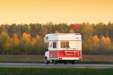 Vintage two-colored recreational vehicle on the road with a beautiful landscape background.