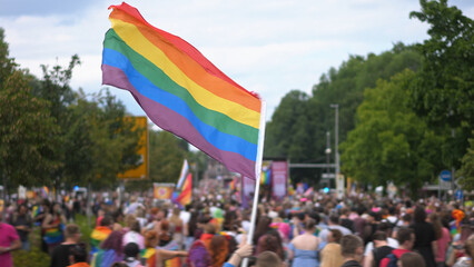 Many people wave rainbow flag. Crowd walk city street. Fun lgbt community symbol. Stop no...