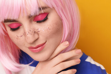 Beautiful woman with bright makeup and glitter freckles on yellow background, closeup