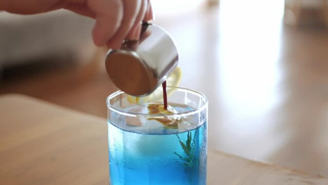 pouring fresh espresso coffee into blue ice fruit juice in a glass,specialty coffee cafe
