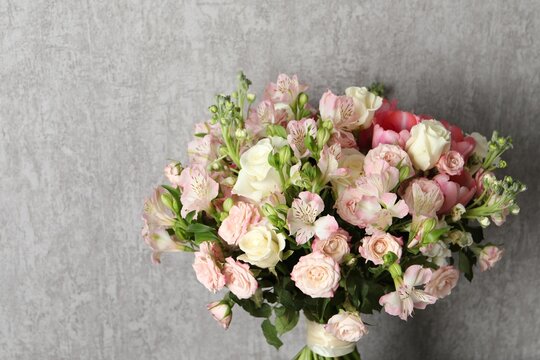 Beautiful bouquet of fresh flowers near grey wall