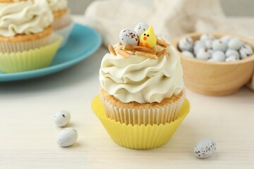 Tasty Easter cupcakes with vanilla cream on light wooden table