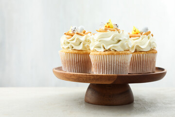 Tasty Easter cupcakes with vanilla cream on gray table, space for text