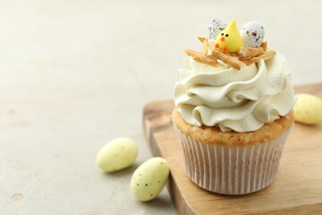 Tasty Easter cupcake with vanilla cream and candies on gray table, space for text