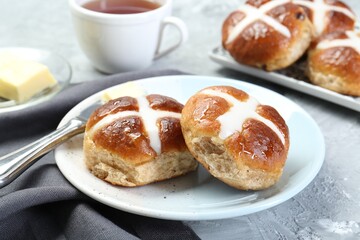 Tasty hot cross buns served on gray textured table, closeup