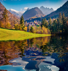 Huge peaks and green pasture reflected in the calm waters of smal lake in outskirts of Gozd Martuljek village. Stunning autumn view of Triglav mountain range in Julian Alps, Slovenia, Europe. - 781890153