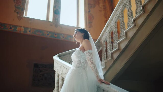 Beautifull fashion bride looking at camera. Sexy confident young brunette woman in white wedding dress posing at camera, smiling. Slow motion background of nature. 