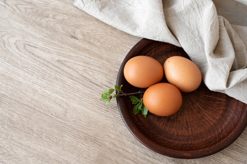 Natural organic eggs on brown plate, on wooden table background, flat lay, copy space. Aesthetic minimal Easter sill life, rustic style
