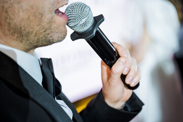 A man in a suit is singing into a microphone at a musical event
