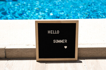 Hello summer text on chalkboard on pool background on summer sunny day