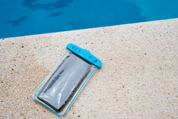 Waterproof case with a smartphone on the background of the pool on a sunny summer day