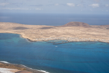 Views of the island of La Graciosa from the viewpoint of El Rio. Turquoise ocean. Blue sky with big white clouds. Caleta de Sebo. Town. volcanoes. Lanzarote, Canary Islands, Spain