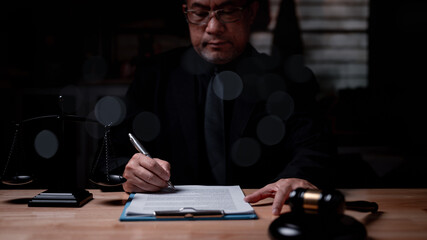 A lawyer man in a suit is writing on a piece of paper. He is wearing a tie and he is in a...