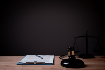 A judge's gavel sits on a desk next to a stack of papers. The scene is set in a courtroom, and the...