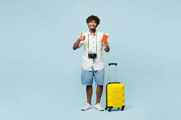 Full body traveler Indian man wears white casual clothes hold bag passport ticket show thumb up...