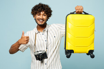 Traveler Indian man wear white casual clothes hold yellow suitcase bag show thumb up isolated on...