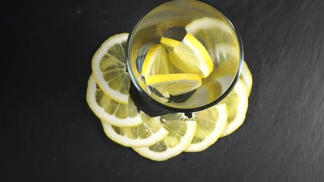 Lemon Fruits with pouring sparkling Water in a Glass on black Background