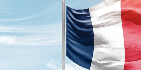 France national flag with mast at light blue sky.