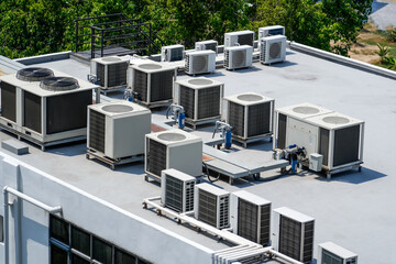 The external units of the commercial air conditioning and ventilation systems are installed on the roof of an industrial building. - obrazy, fototapety, plakaty