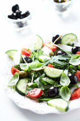 Salad with black Olives, cherry Tomatoes, Cucumber and Rocket on bright Background. Close up.	