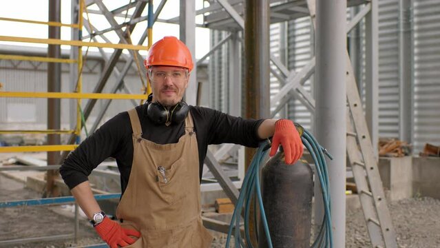 The assembly worker stands near the autogen on the construction site. A look at the camera.