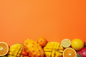 Set of tropical fruit on orange background, top view