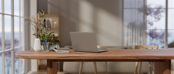 A laptop computer and decor on a wooden table by the window in a cozy contemporary room. - 781920760