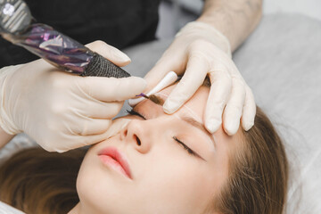 A cosmetologist applies permanent makeup to the eyebrows - eyebrow tattoo. eyebrow perm