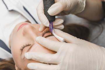 A cosmetologist applies permanent makeup to the eyebrows - eyebrow tattoo. eyebrow perm