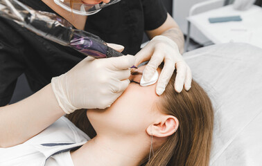 A cosmetologist applies permanent makeup to the eyebrows - eyebrow tattoo. eyebrow perm