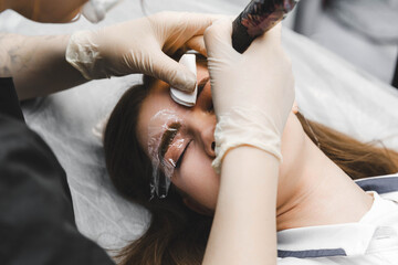A cosmetologist applies permanent makeup to the eyebrows - eyebrow tattoo. eyebrow perm