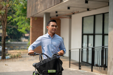 A happy, carefree Asian businessman going to work with his bicycle on a sunny day.