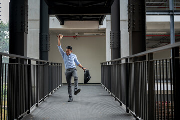 A cheerful Asian businessman walks along a corridor, exuding extreme happiness through his gestures.