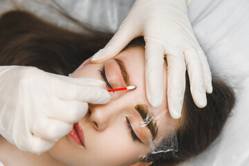 A cosmetologist applies permanent makeup to the eyebrows - eyebrow tattoo. eyebrow perm