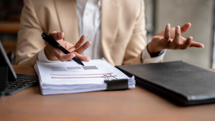 A businessman is reviewing business document at a table, having a meeting with his team.