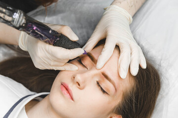 A cosmetologist applies permanent makeup to the eyebrows - eyebrow tattoo. eyebrow perm