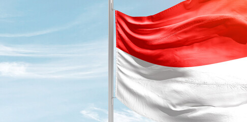 Indonesia national flag with mast at light blue sky.