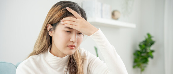 Fototapeta premium Headache, female having migraine pain, bad health, Asian woman feeling stress and headache, Office syndrome, sad tired touching forehead having migraine or depression, irritated girl, sadness grief
