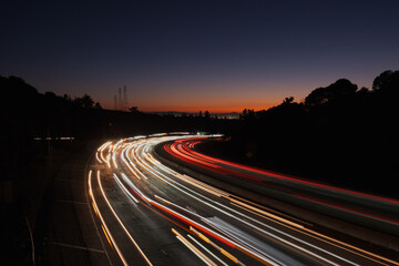View of light streaks created by traffic coming from San Francisco and Oakland at sunset, as seen from an overpass over Highway 24. - obrazy, fototapety, plakaty