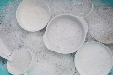 Plates and bowl soaking in foam of dishwashing liquid