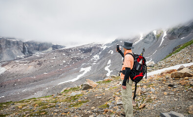 Hiker taking photos using a smartphone at Skyline Trail. Mountains in the cloud. Mt Rainier National Park. Washington State. - 781936590