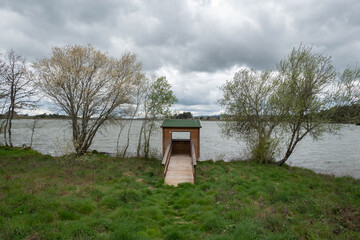 Refúgio Tranquilo: Cabana de madeira à beira do lago sob uma tempestade imponente no horizonte