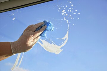 A woman washes a window.  Household chore