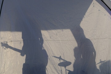 Shadows of band members playing live music in a pavilion