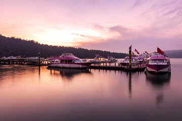 beautiful sunset at lake pier, tourist boats at twilight, long exposure shot for smooth water
