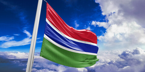 The Gambia national flag cloth fabric waving on beautiful Blue Sky Background.