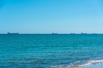 Beautiful view of blue water and line of tankers sailing in the background